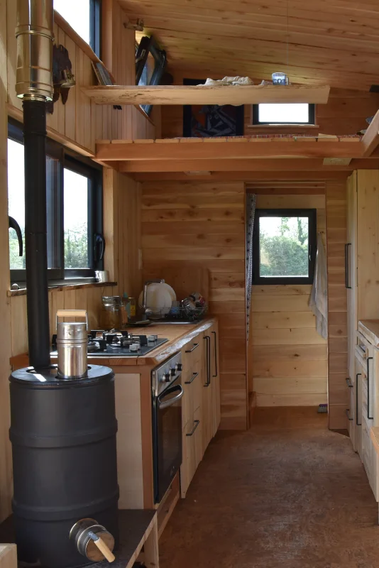 Habitat Low Tech - Intérieur avec vue sur le poêle de masse, la cuisine et la salle de bain